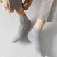 Five pairs of soft bamboo fiber socks in black and gray, worn up to mid-calf