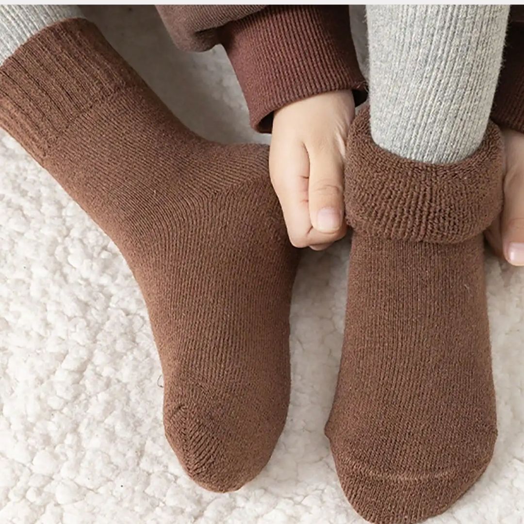 Five pairs of thick knit winter socks for kids, worn up to mid-calf