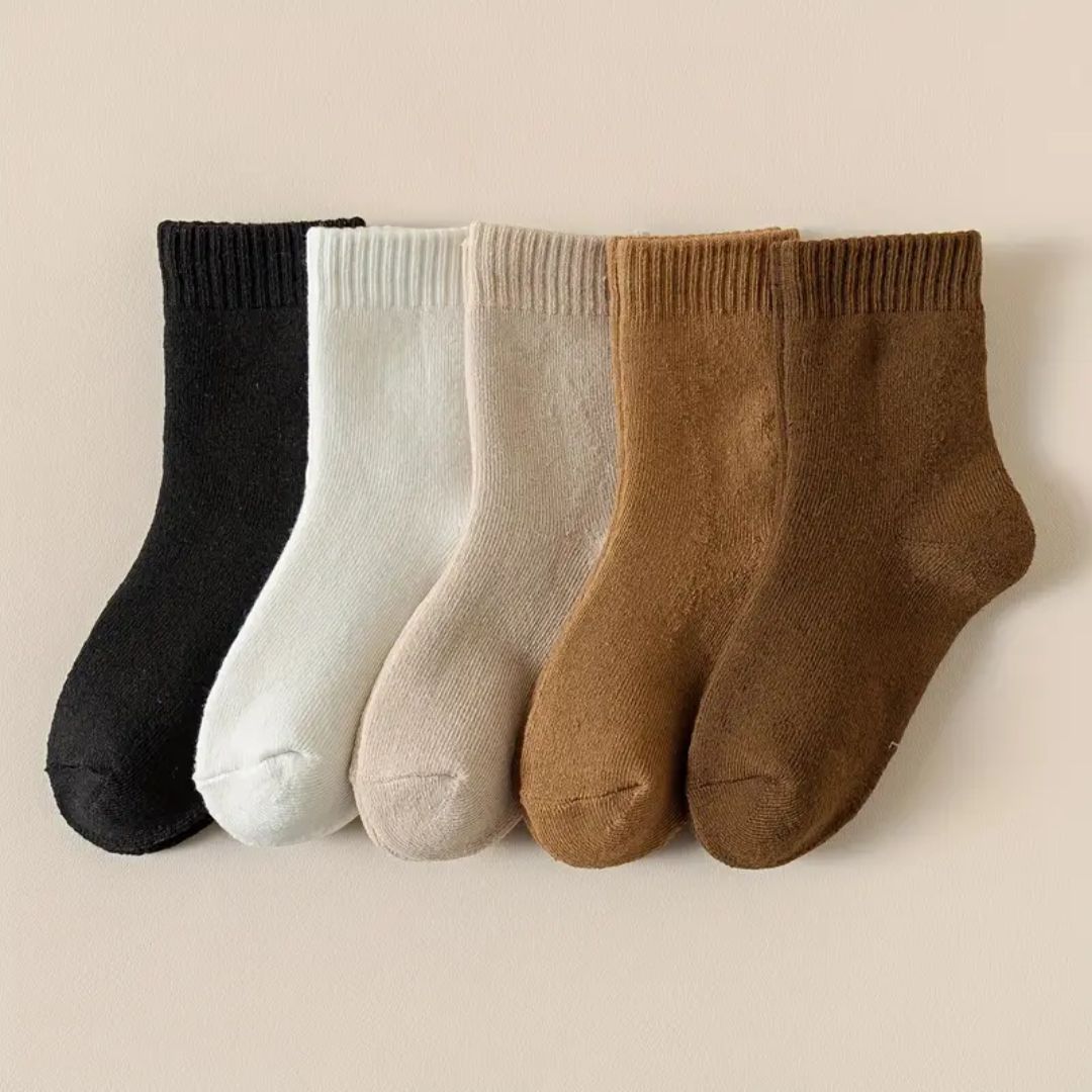 Five pairs of thick knit winter socks for kids, worn up to mid-calf