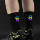 Black cycling socks with reflective stripes, worn high on the calf