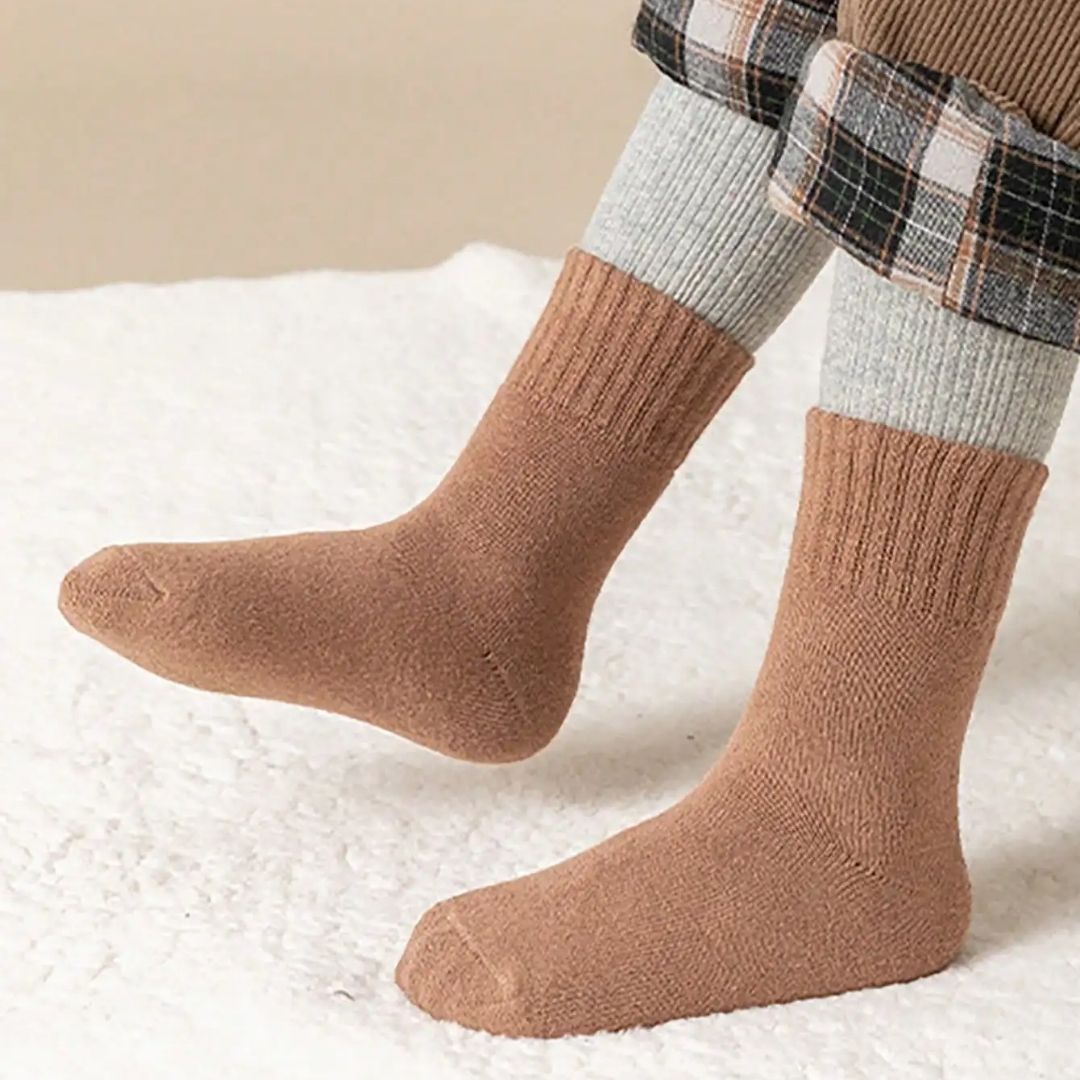 Five pairs of thick knit winter socks for kids, worn up to mid-calf