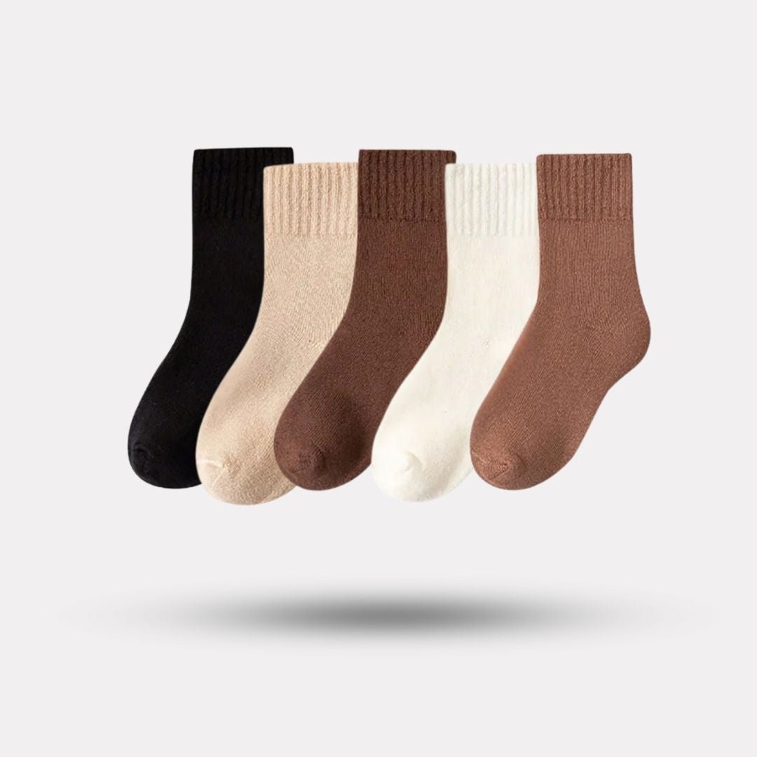 Five pairs of thick knit winter socks for kids, worn up to mid-calf