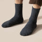 Thick merino wool winter socks in gray, black, khaki and brown, pulled up over the calf