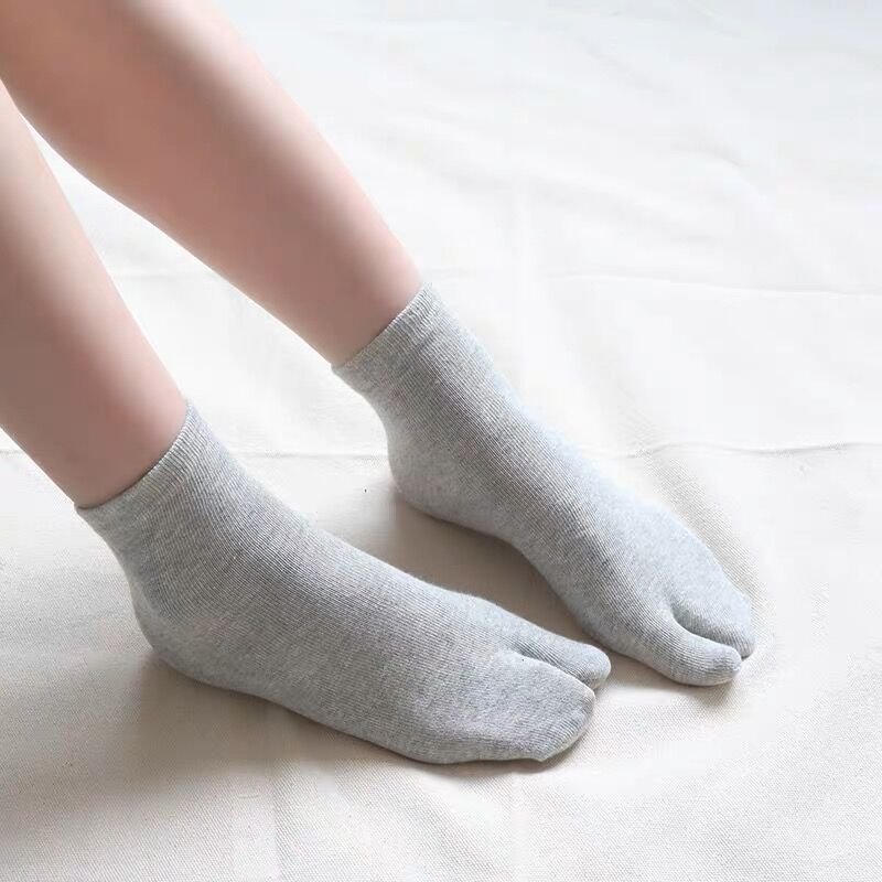 Gray, black and white socks shaped to fit around a bunion corrector on the big toe