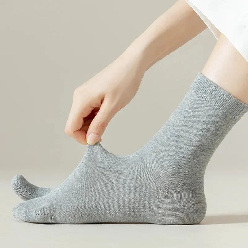 Gray, black and white socks shaped to fit around a bunion corrector on the big toe