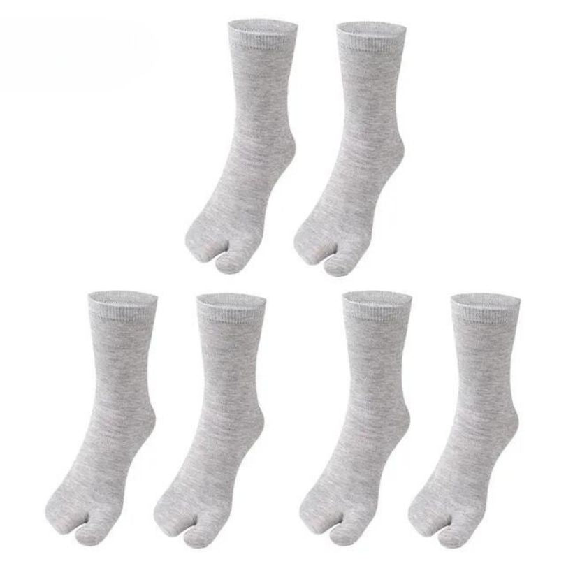 Gray, black and white socks shaped to fit around a bunion corrector on the big toe
