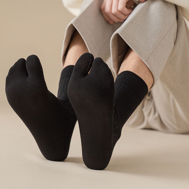 Gray, black and white socks shaped to fit around a bunion corrector on the big toe