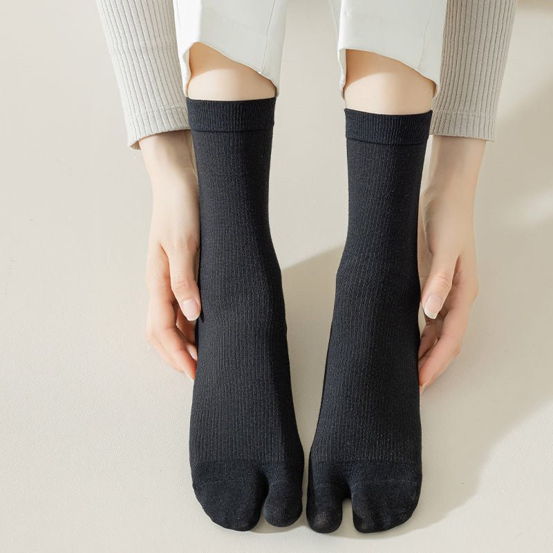 Gray, black and white socks shaped to fit around a bunion corrector on the big toe