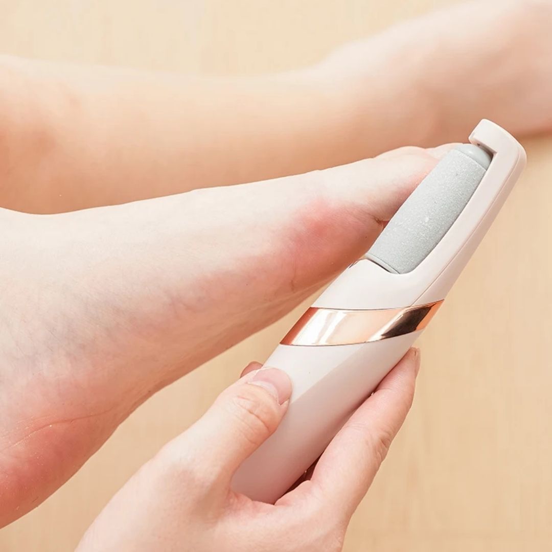 Pink handheld electric callus remover with a rotating roller head for the heel